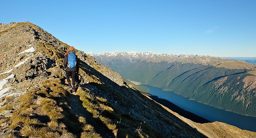 Woman Hiking Towards Mountain Summit High Above Lake Rotoiti. Nelson Lakes National Park, New Zealand