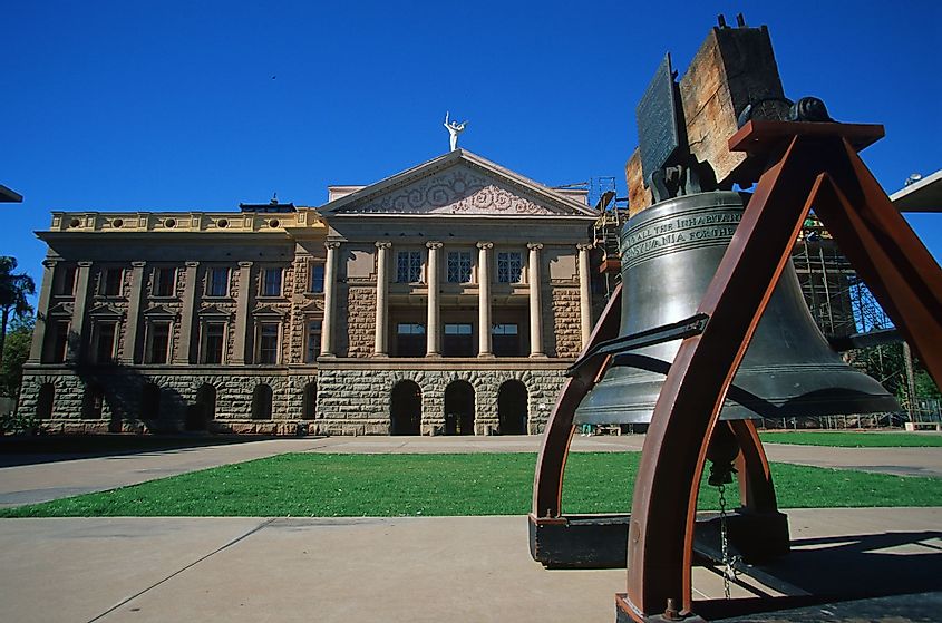A view of the Arizona State Capitol with a bell in front
