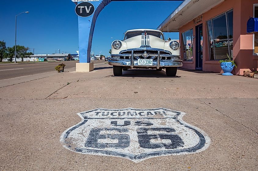 Worn out stamp of route 66 on the pavement in front of an antique pontiac car. Tucumcari, New Mexico, US.
