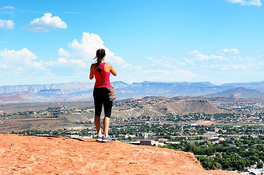 Woman atop Sugarloaf rock formation overlooking St. George, Utah.