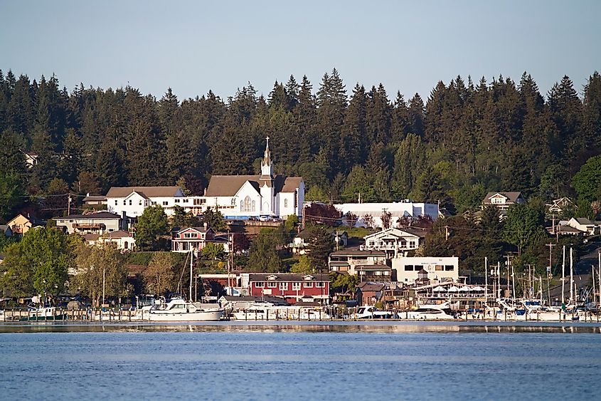 An old church sits prominently atop a hill overlooking the charming town of Poulsbo in Washington State, surrounded by lush greenery and historic buildings.