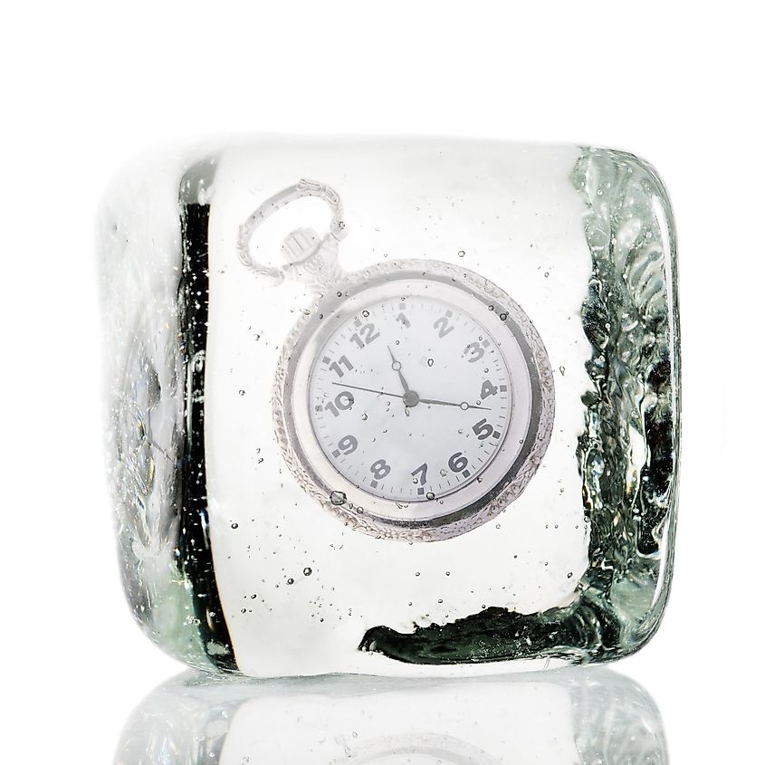 A frozen clock encased in a block of ice, representing the concept of time being suspended or frozen in a moment.