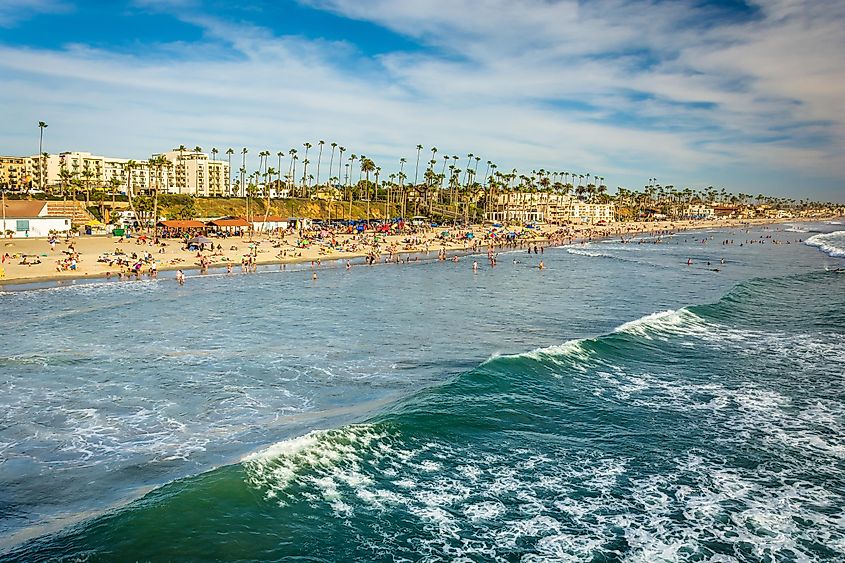 View of the beach and waves in the Pacific Ocean from the pier in Oceanside, California.