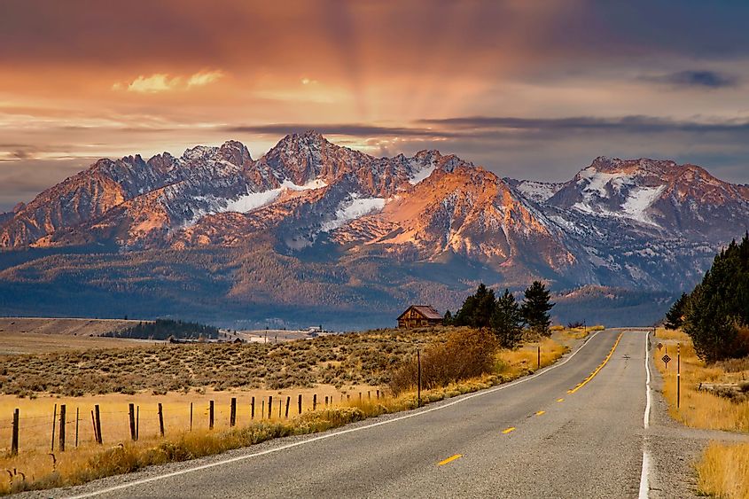The Sawtooth Mountains and a log cabin at sunrise and highway 75 leading to Stanley, Idaho