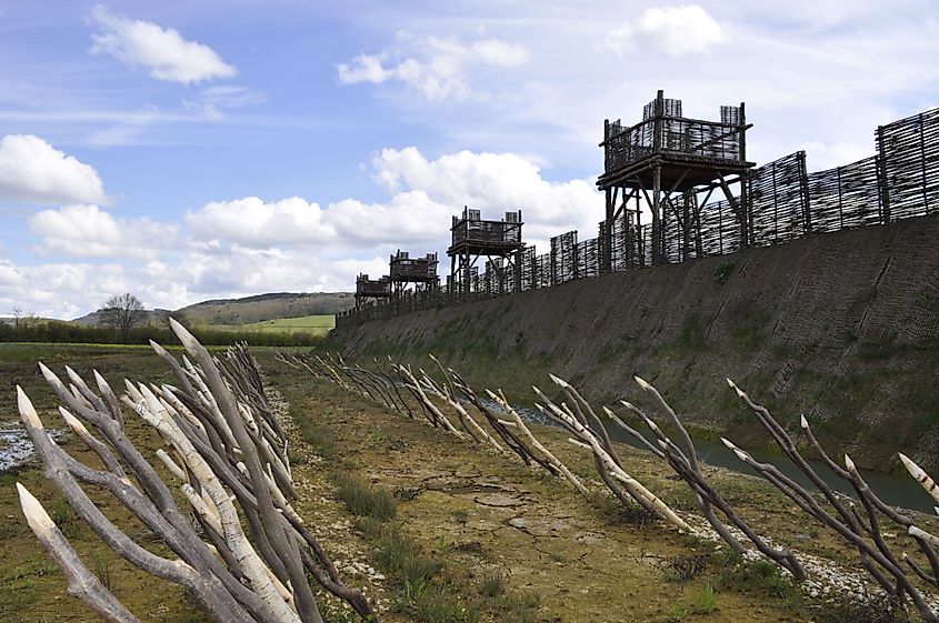 Modern recreation of the Alesia fortifications, featuring rows of stakes in front of a moat, a high banked approach, and regular towers for Roman sentries.