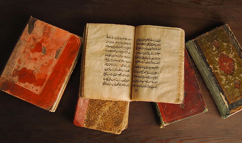 Stack of open ancient books in Arabic.