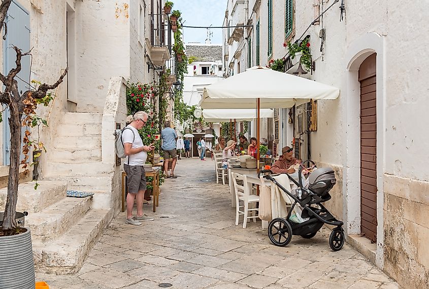 Tourists enjoying the outdoor restaurants in the ancient village Locorotondo, in province of Bari.