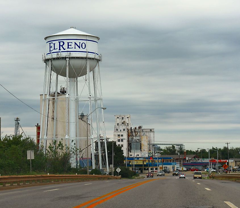 Water tower in El Reno, Oklahoma with buildings and vehicles in the background.