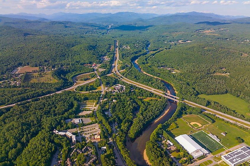 Pemigewasset River and Interstate Highway 93 north bound aerial view with White Mountain National Forest at the background in summer near town center of Plymouth, New Hampshire.