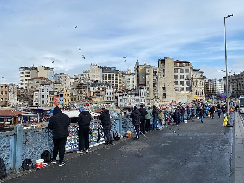 A row of fishermen casting over a city bridge in Istanbul.