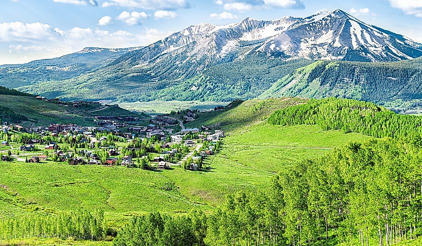 Crested Butte, Colorado town cityscape high angle view from Snodgrass hiking trail in summer with alpine meadows and aspent trees forest grove
