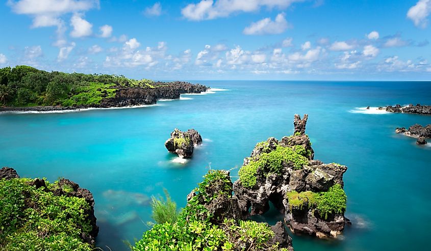 Road to Hana, Black Sand Beach, Waianapanapa State Park, Maui. Blue water and small lush island.