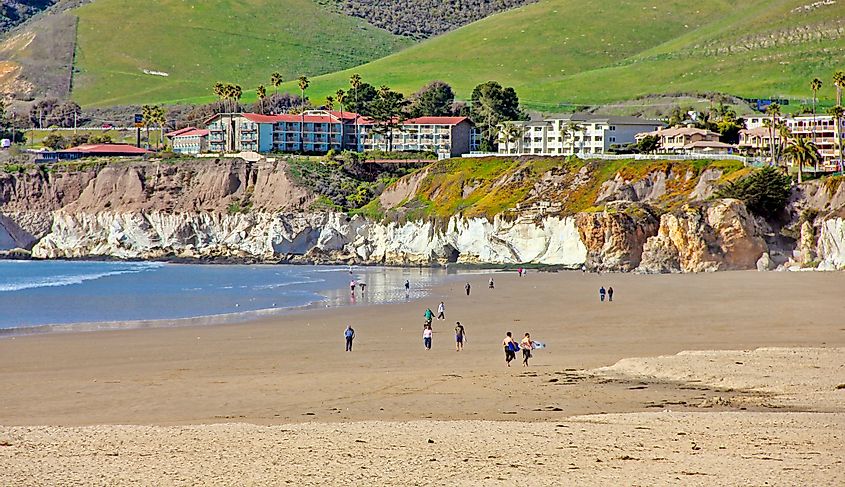 Beachcombers stroll along the shore in Pismo Beach, California