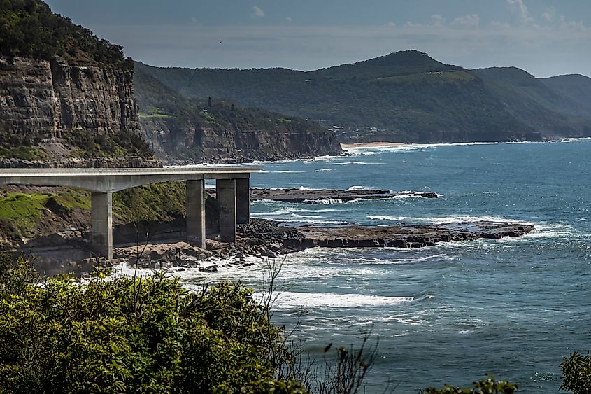Coastal bridge along cliffs overlooking the ocean and rocky shoreline.