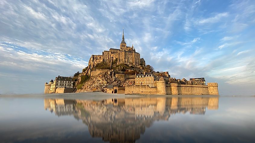 Beautiful Mont Saint Michel with water reflection and clouds on blue sky, France.
