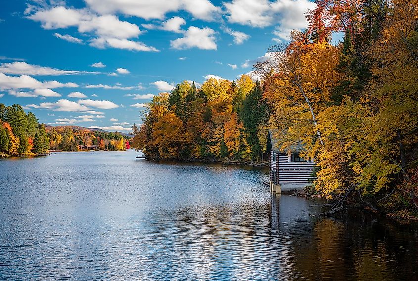 Autumn leaves and trees surround boathouse on Chateaugay Lake in Ellenburg New York State