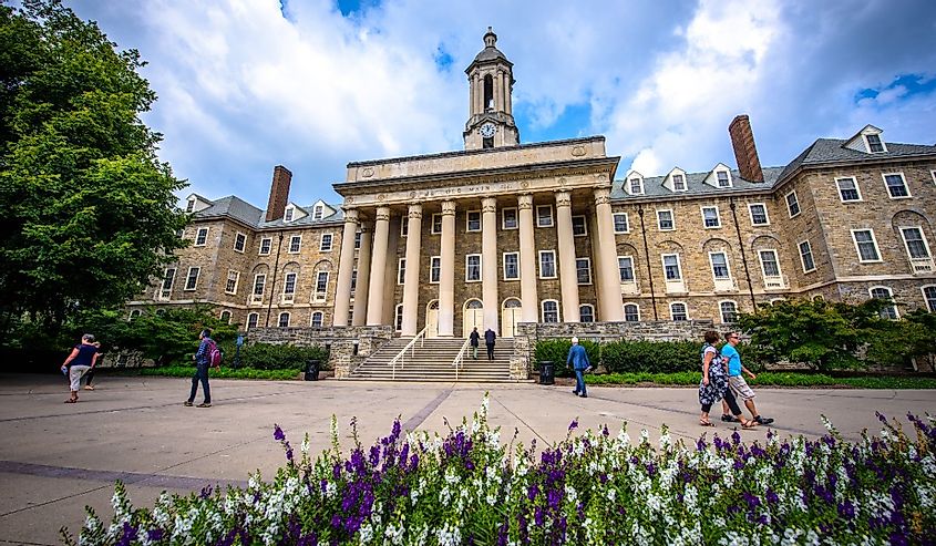 Students and adults walk in front of the Old Main building, on the campus of Penn State University, in State College, Pennsylvania