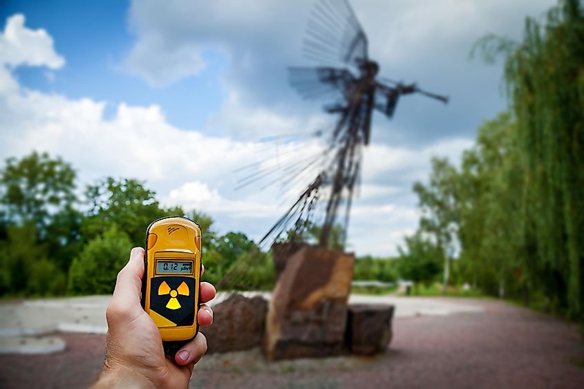 Dosimeter Being Held Near a Monument that Commemorates the Chernobyl Accident