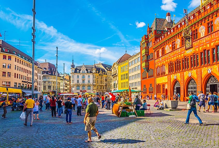  People are strolling on the Marktplatz in front of the red town hall in Basel, Switzerland