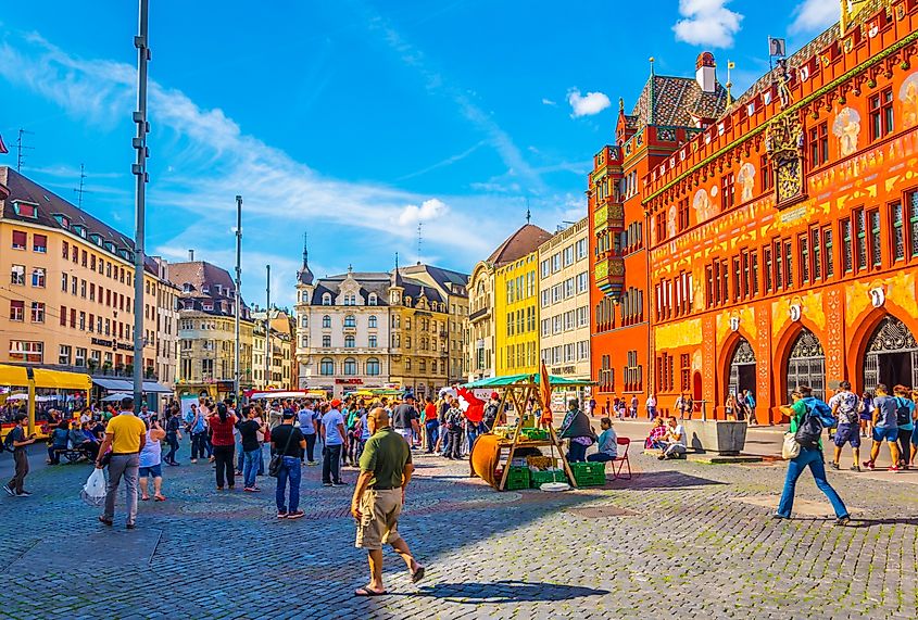 People are strolling on the Marktplatz in front of the red town hall in Basel, Switzerland