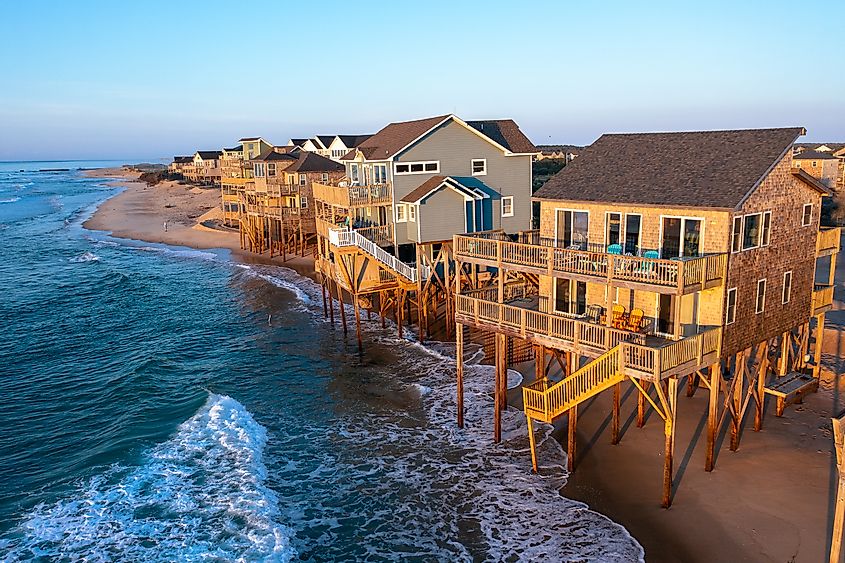 Aerial view of homes right on the shoreline in the ocean during high tide in Buxton North Carolina Outer Banks