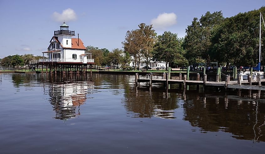 This is the 1886 Roanoke River Lighthouse in Edenton, NC sitting in sparkling waters and surrounded by ships.