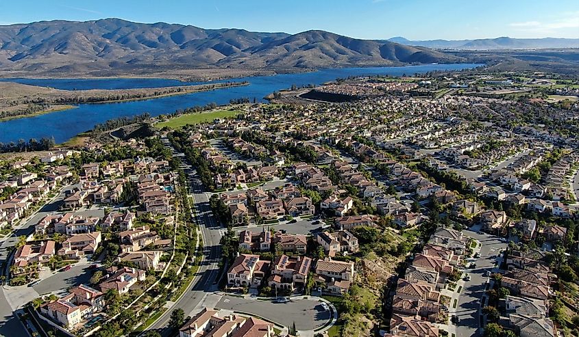 Aerial view of identical residential subdivision house with big lake and mountain on the background during sunny day in Chula Vista, California