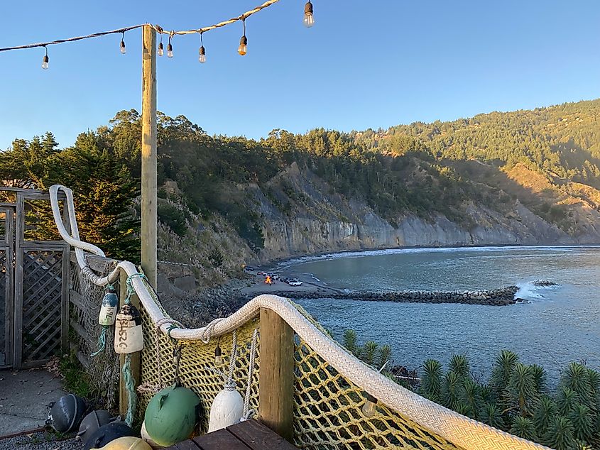The view from a cliffside beach patio, looking down on a tidal beach and a parking lot bonfire.