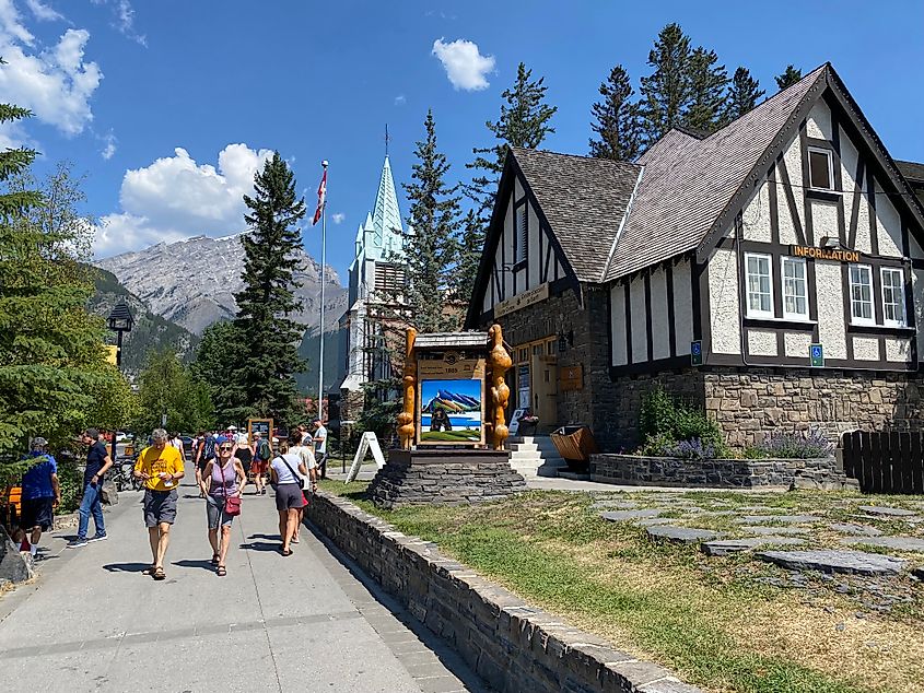 Pedestrians walk past the elegant Banff Visitor Center on a bluebird day. 