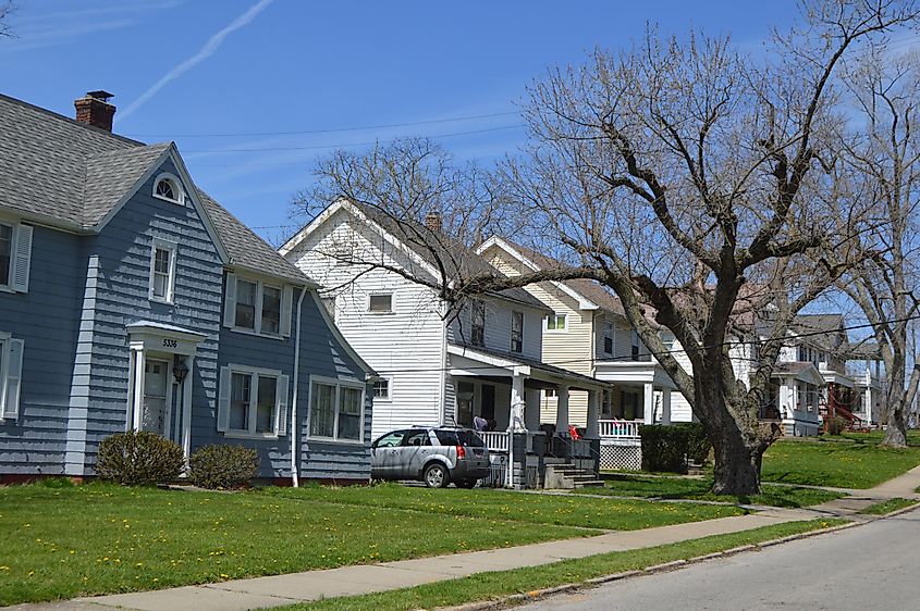 Row of charming suburban houses along the western side of Vine Street at its southern end in Maple Heights, Ohio, featuring well-maintained front yards, varying architectural styles from classic to modern, and tree-lined sidewalks under a bright, open sky.