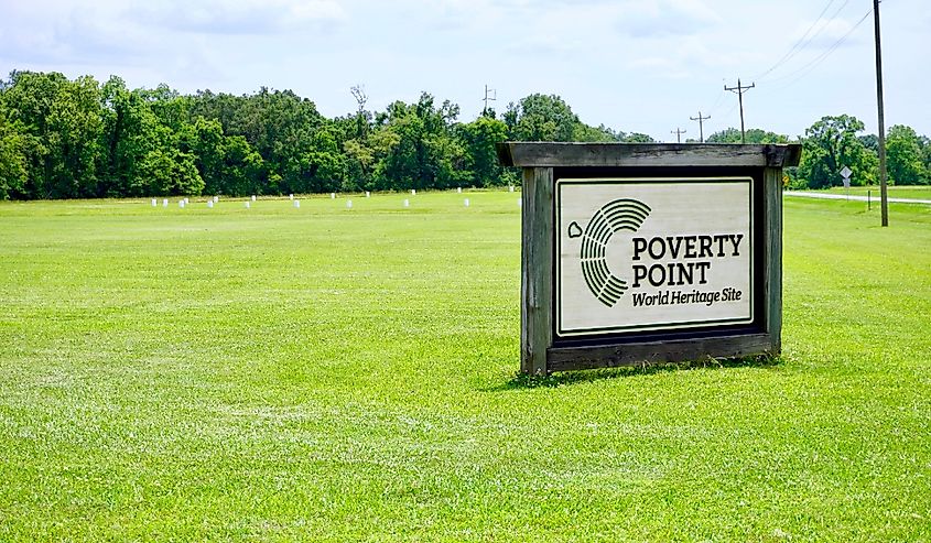 Poverty Point State Historical Site is a prehistoric monumental earthworks site constructed by Poverty Point culture. World Heritage Site sign, white wood post markers circle.