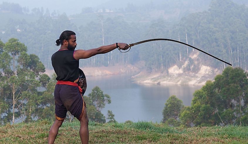 Indian fighter doing exercises with Urumi sword during Kalaripayattu marital art demonstration in Kerala, South India