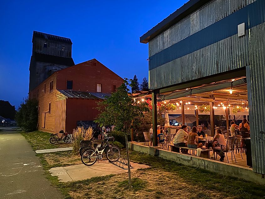 Evening social festivities at an outdoor brewery next to a grain elevator.