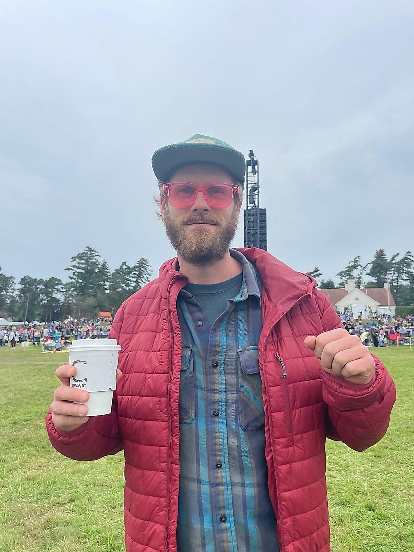 The author in a red puffy jacket and pink sunglasses dancing with a cup of coffee in hand.