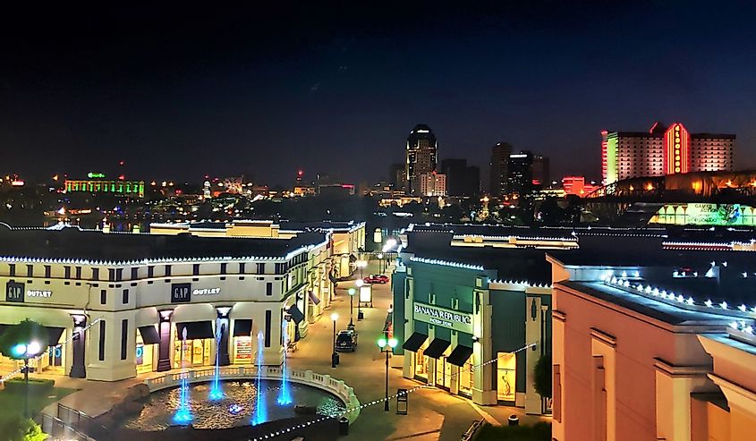 Fountains and stores at night at Louisiana Boardwalk Mall with Shreveport Skyline in background