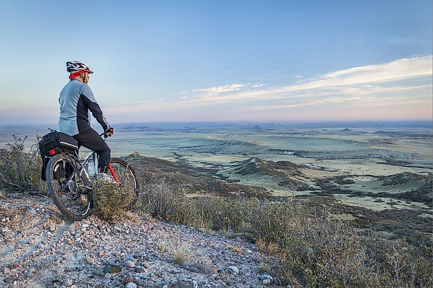A man on a mountain bike taking in a view of rolling prairie at dusk, Soapstone Prairie Natural Area near Fort Collins, Colorado