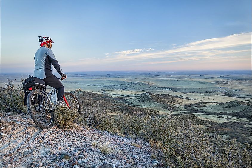 A senior man on a mountain bike contemplating a view of rolling prairie at dusk, Soapstone Prairie Natural Area near Fort Collins, Colorado