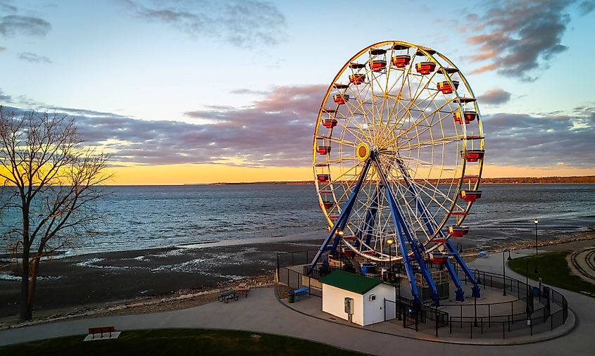 Editorial Photo Credit: Photo Spirit via Shutterstock. View of the Ferris wheel at Bay Beach Amusement Park in Green Bay Wisconsin during sunset, with golden sky and lakefront in the background.