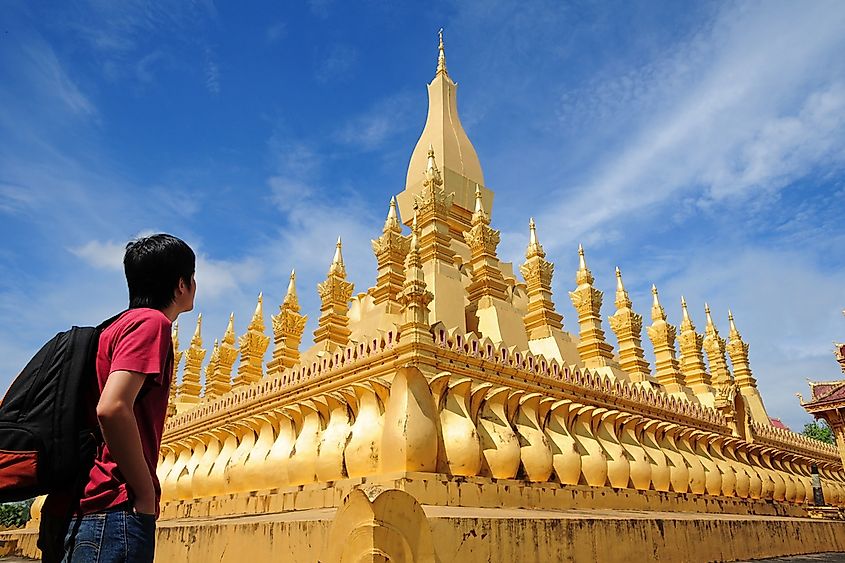 A backpacker stands outside of the Wat Pha-That Luang in Laos.