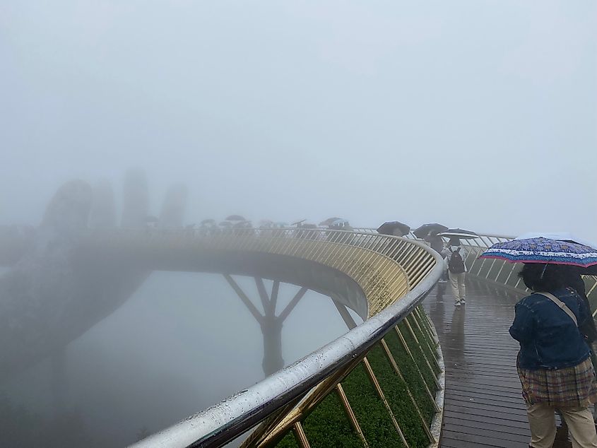 A curved viewing platform supported by a giant hand sculpture - completely shrouded in fog.