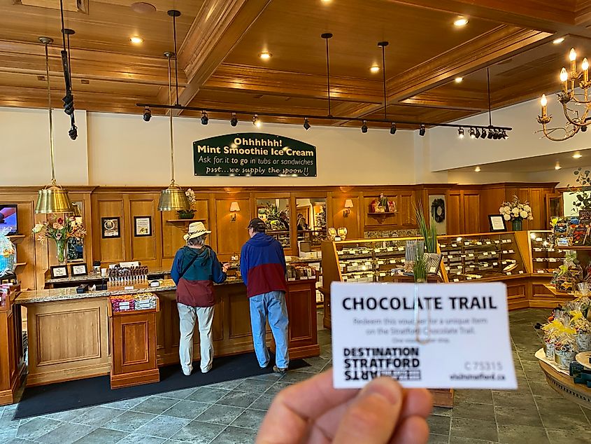 The photographer holds up a Chocolate Trail ticket from within a large chocolate shop.