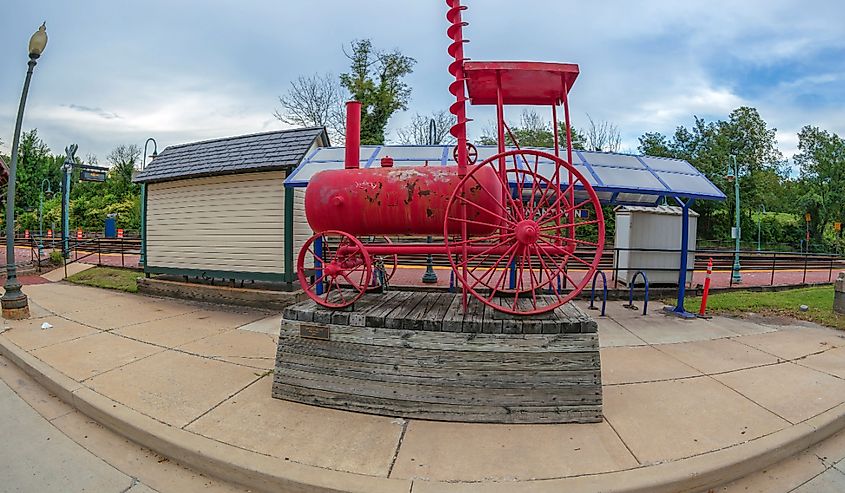 Old functional railway station with red metal train structure out front.