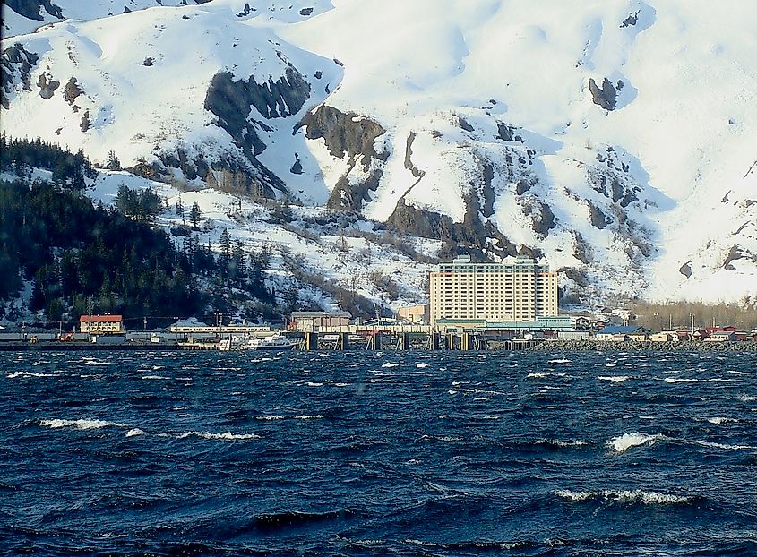 A scenic faraway view from the water of the Begich Towers against a snowy mountain backdrop.