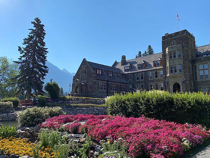 A large, Tudor-style building stands before a colorful garden. 
