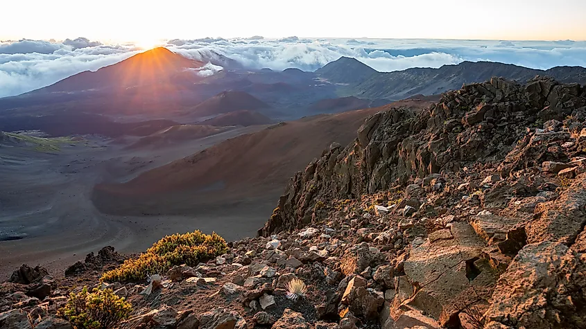 The sun rises dramatically over the dormant volcano and jagged peaks of Haleakala National Park on the island of Maui, Hawaii.