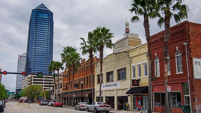 Cars and palm trees line the street of downtown Jacksonville with a mix of modern and historic architecture, via RozenskiP / Shutterstock.com