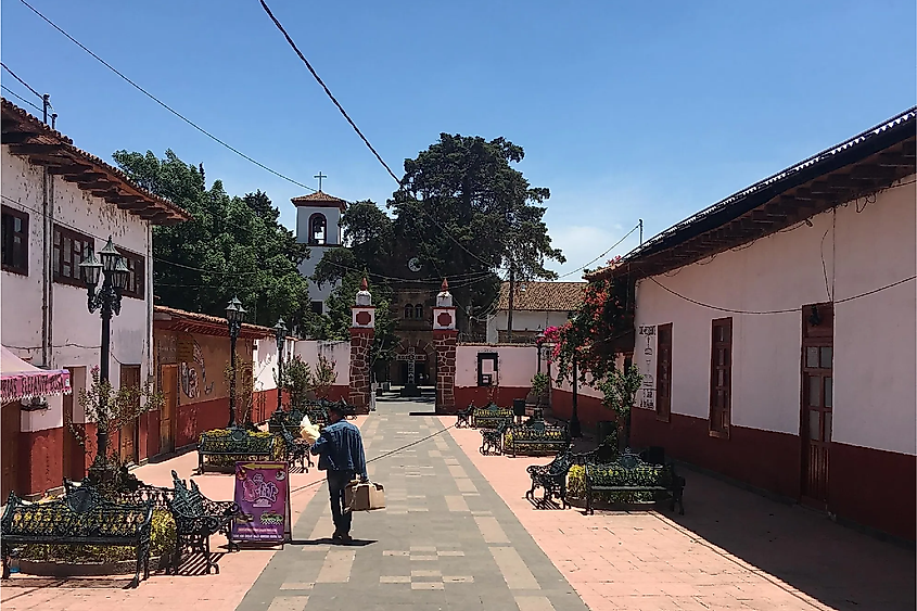 A man walks down a quiet side road towards the town's main church