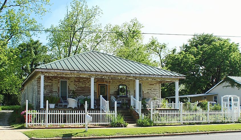 House with white picket fence, white posts and white chairs on front porch in Hartford, Alabama.