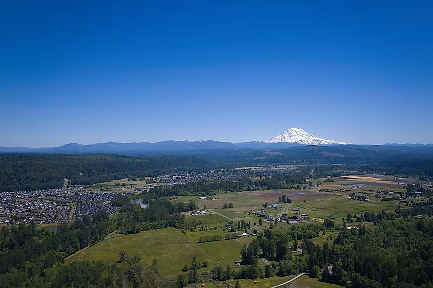 An aerial photo looking over Puyallup and Orting, WA with a view of Mt. Rainier under a clear blue sky.