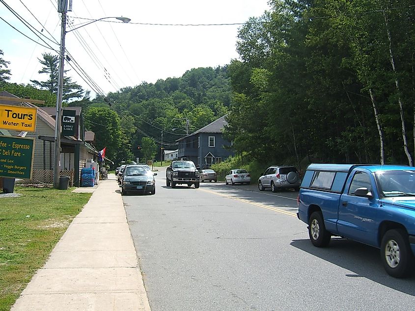 Street scene in Long Lake, New York, with a few cars parked along the roadside.